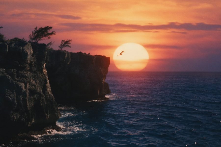A cliff diver silhouetted above the sea at sunset on the West End cliffs, Negril